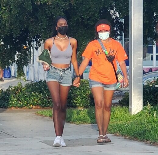 Mother and daughter holding hands while walking on a sidewalk in Miami, Florida.